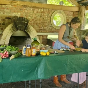 A woman and child preparing food on an outdoor table.