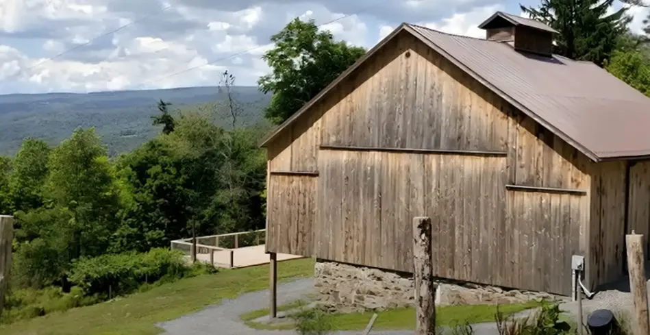 A barn with a fence and trees in the background