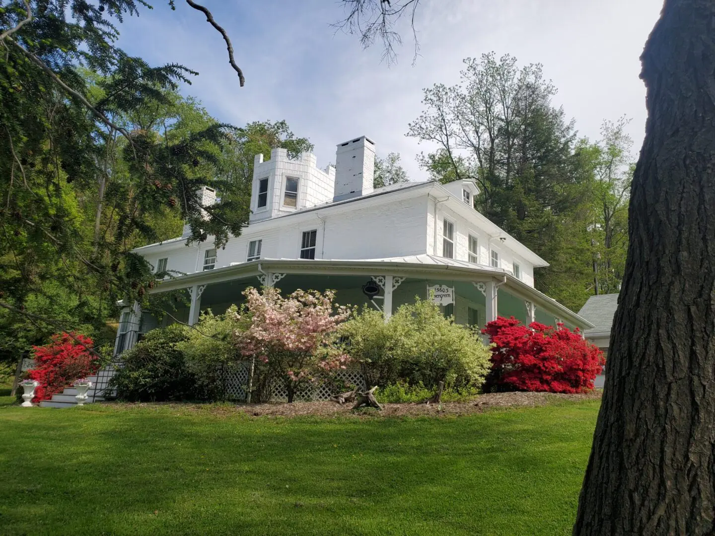 A large white house sitting on top of a green hill.