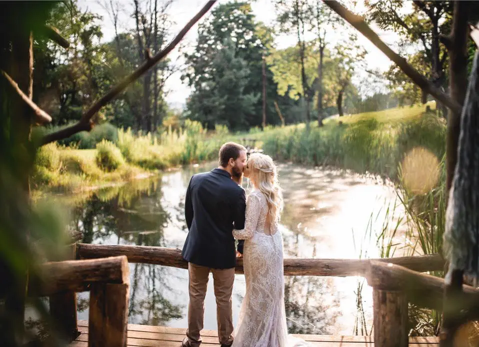 A man and woman standing on the bridge over water.