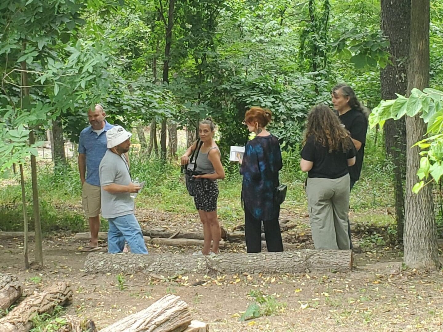 Five people standing in a wooded area.