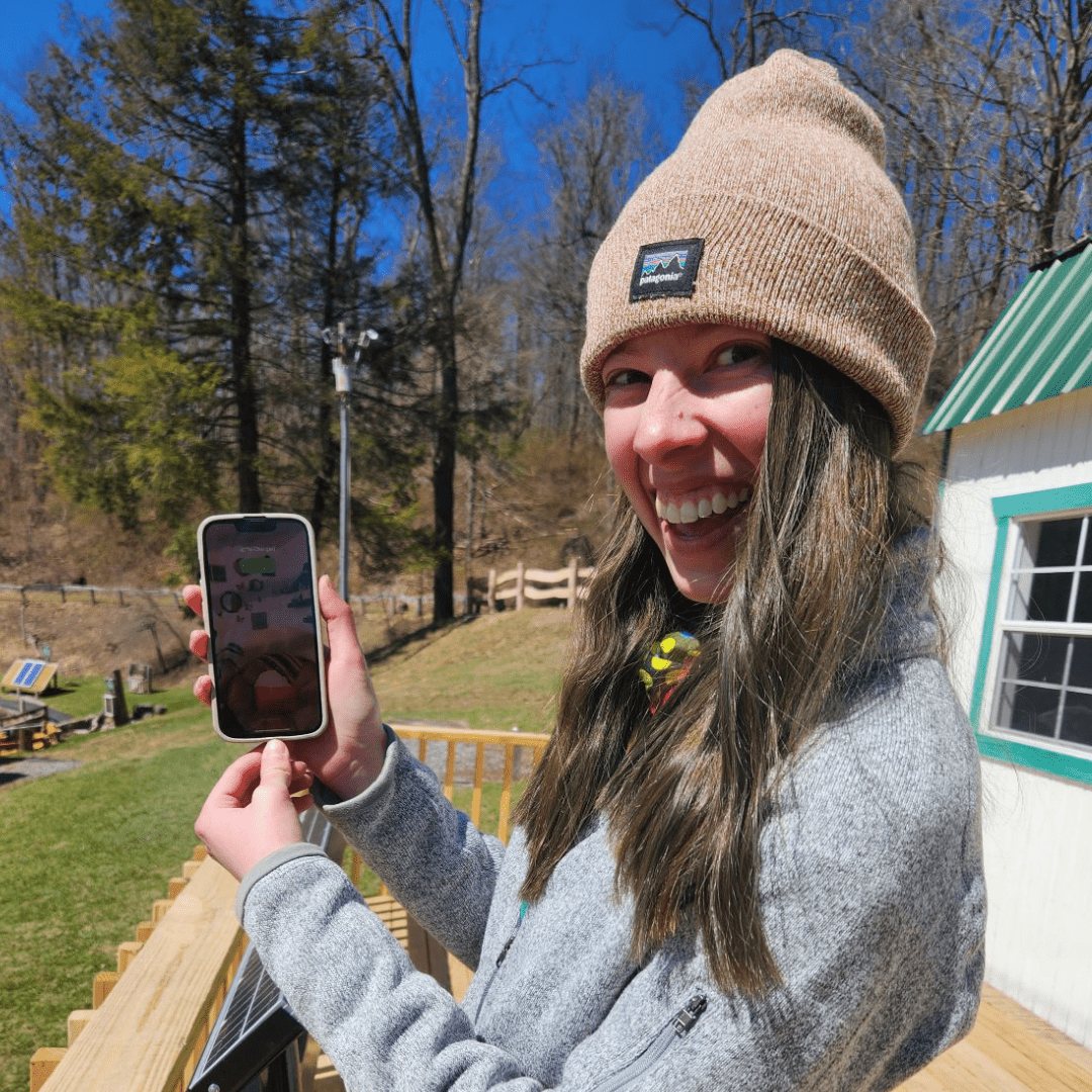 Smiling woman in beanie holding a phone.