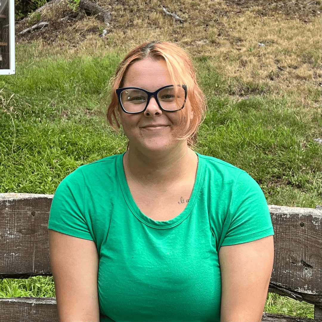 Woman wearing glasses sits on a bench.